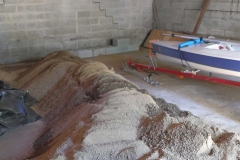 Piles of soil in garage with our laser boat in background